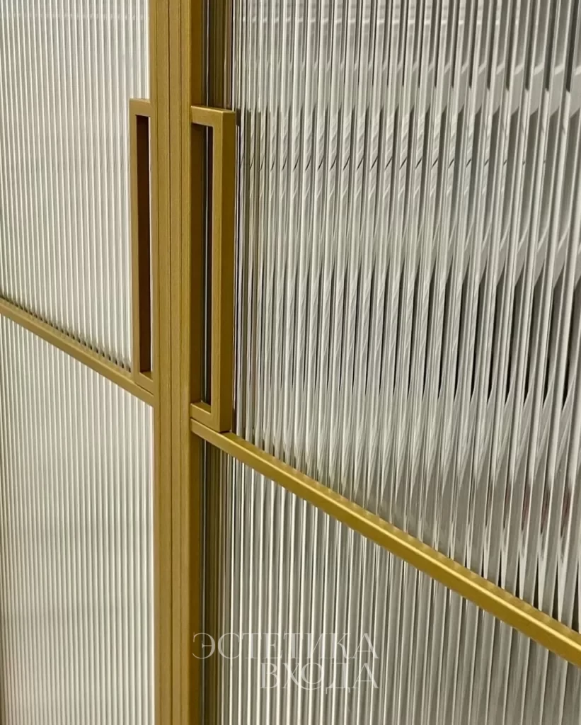 Перегородка для гардеробной комнаты с радиальным золотым профилем и вставками из рифленого стекла.