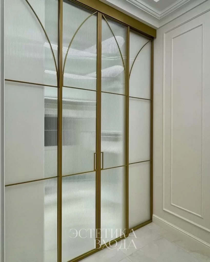 Перегородка для гардеробной комнаты с радиальным золотым профилем и вставками из рифленого стекла.