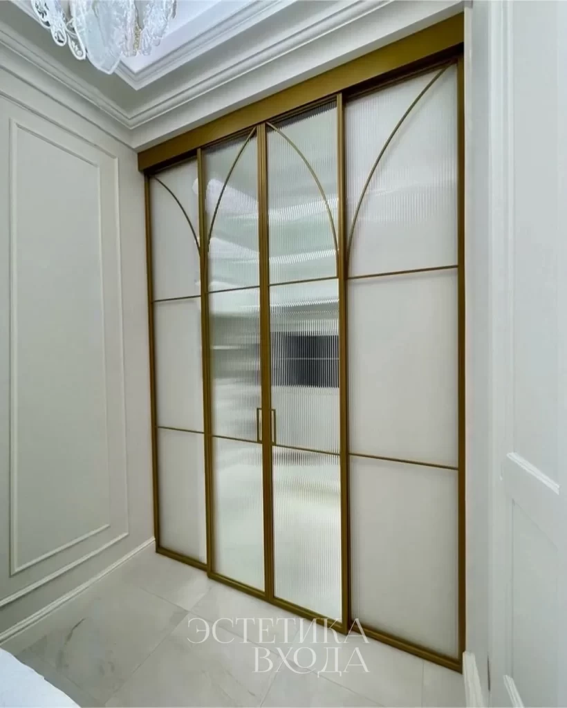 Перегородка для гардеробной комнаты с радиальным золотым профилем и вставками из рифленого стекла.